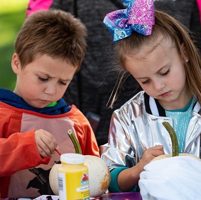 a boy and a girl decorating pumpkins